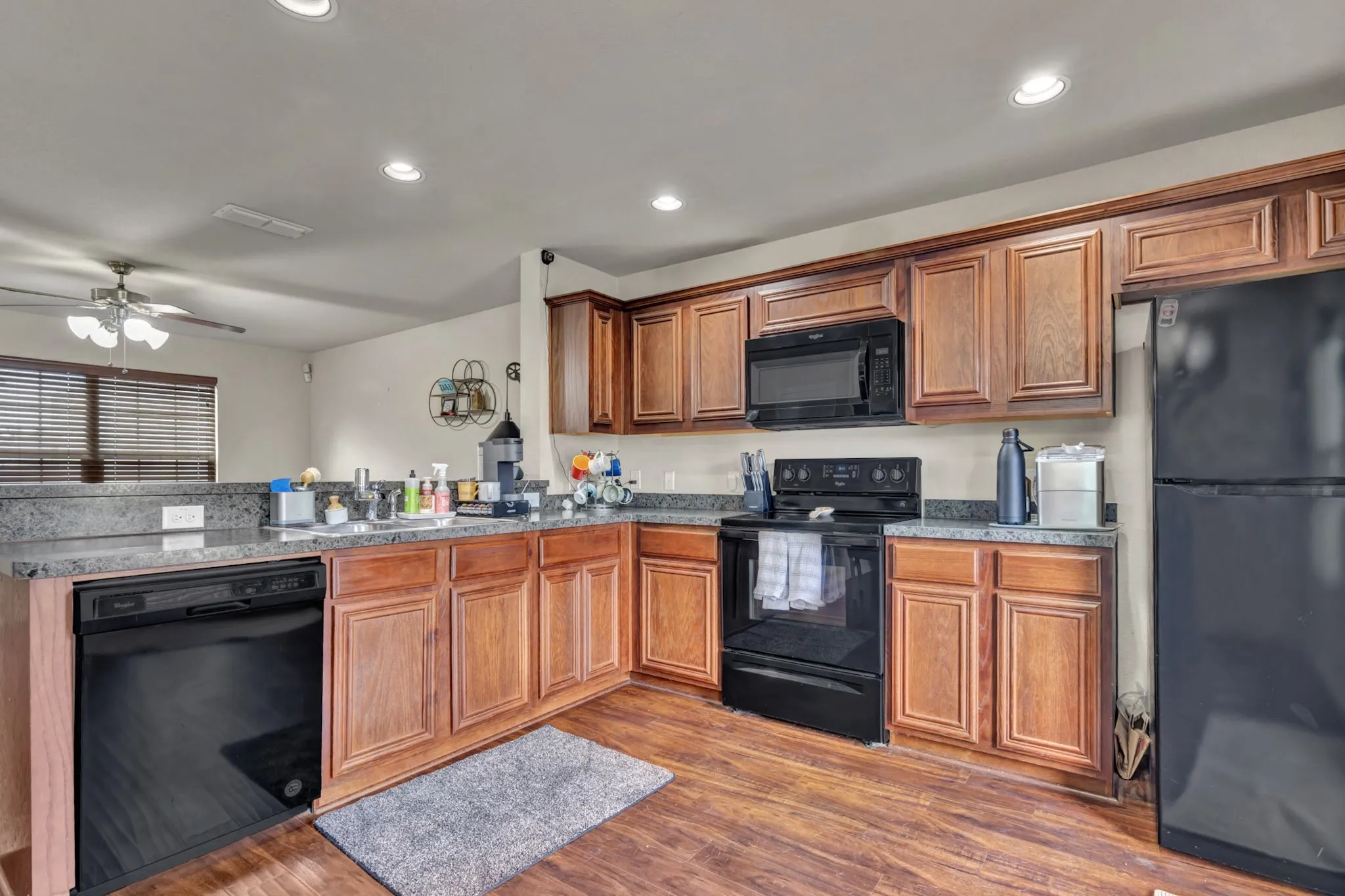 The kitchen features wood cabinetry, black appliances, and granite countertops
