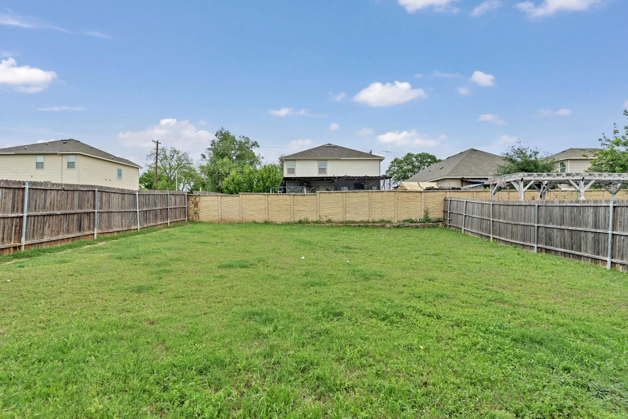 Expansive backyard with a lush green lawn, bordered by wooden fencing and a privacy wall