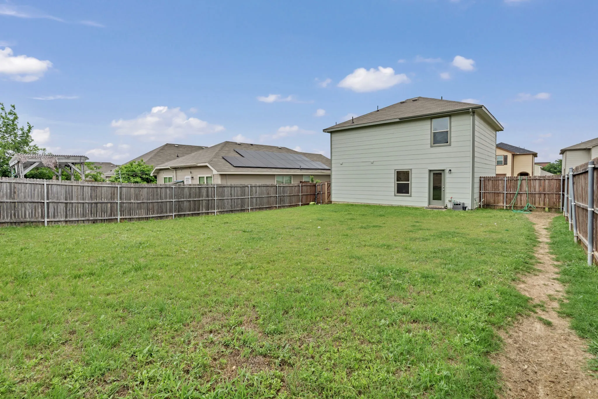 The property features a large yard with a lawn, enclosed by a wooden fence, and includes a two-story exterior