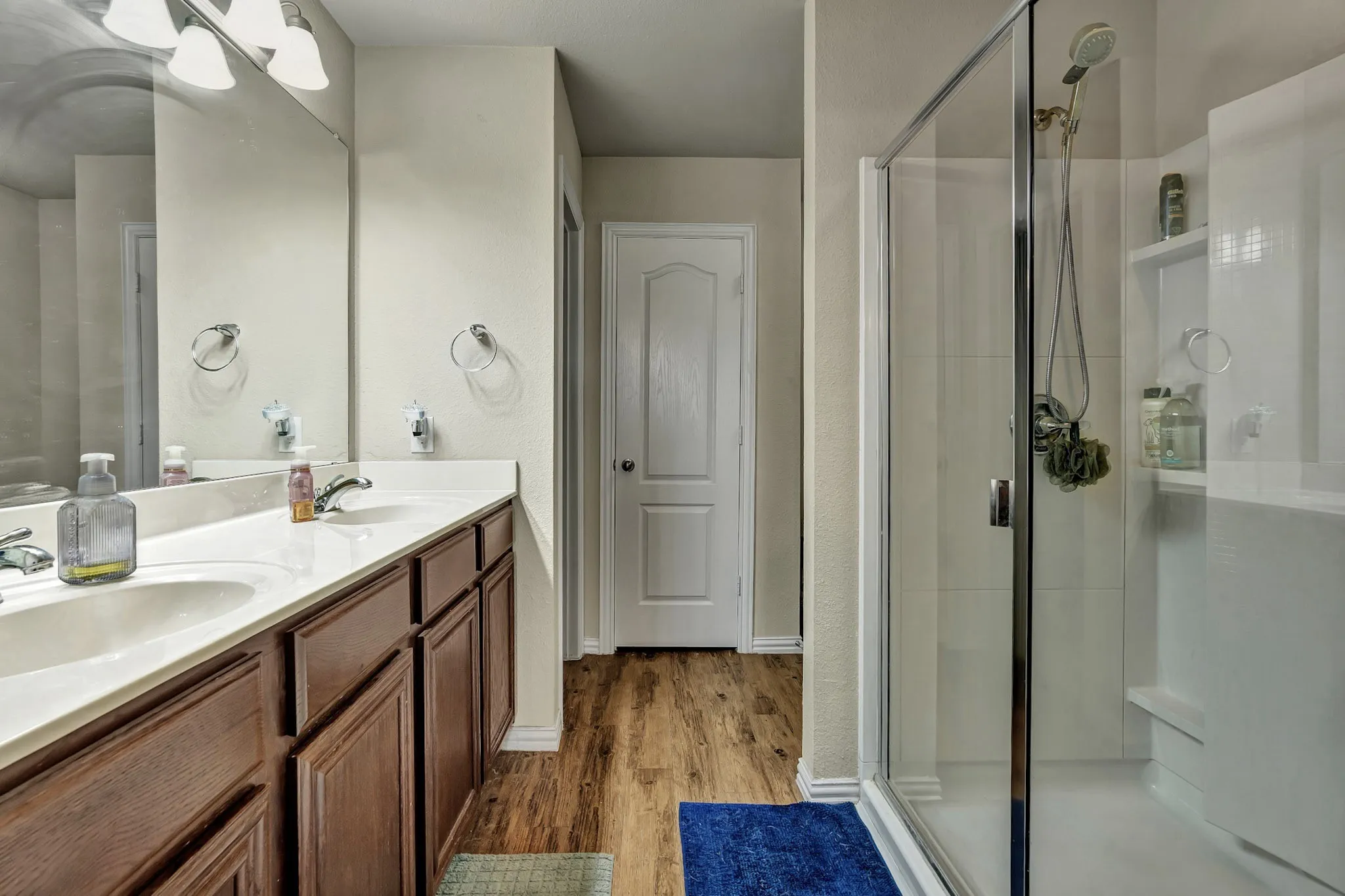 The bathroom features a dual vanity with dark wood cabinetry, white countertops, and a large mirror