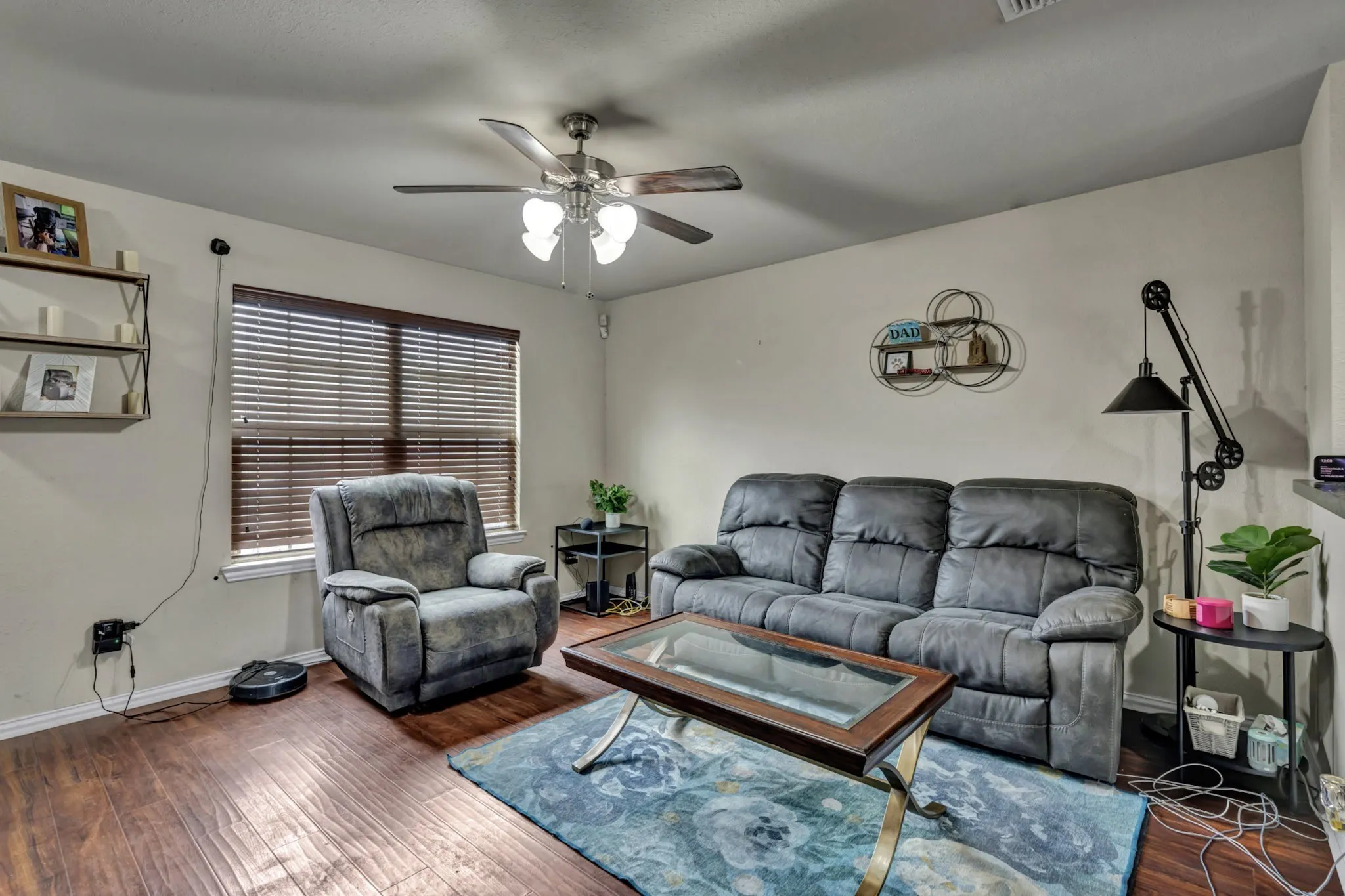 Living room featuring hardwood style flooring, a window with blinds, and an overhead ceiling fan with lighting