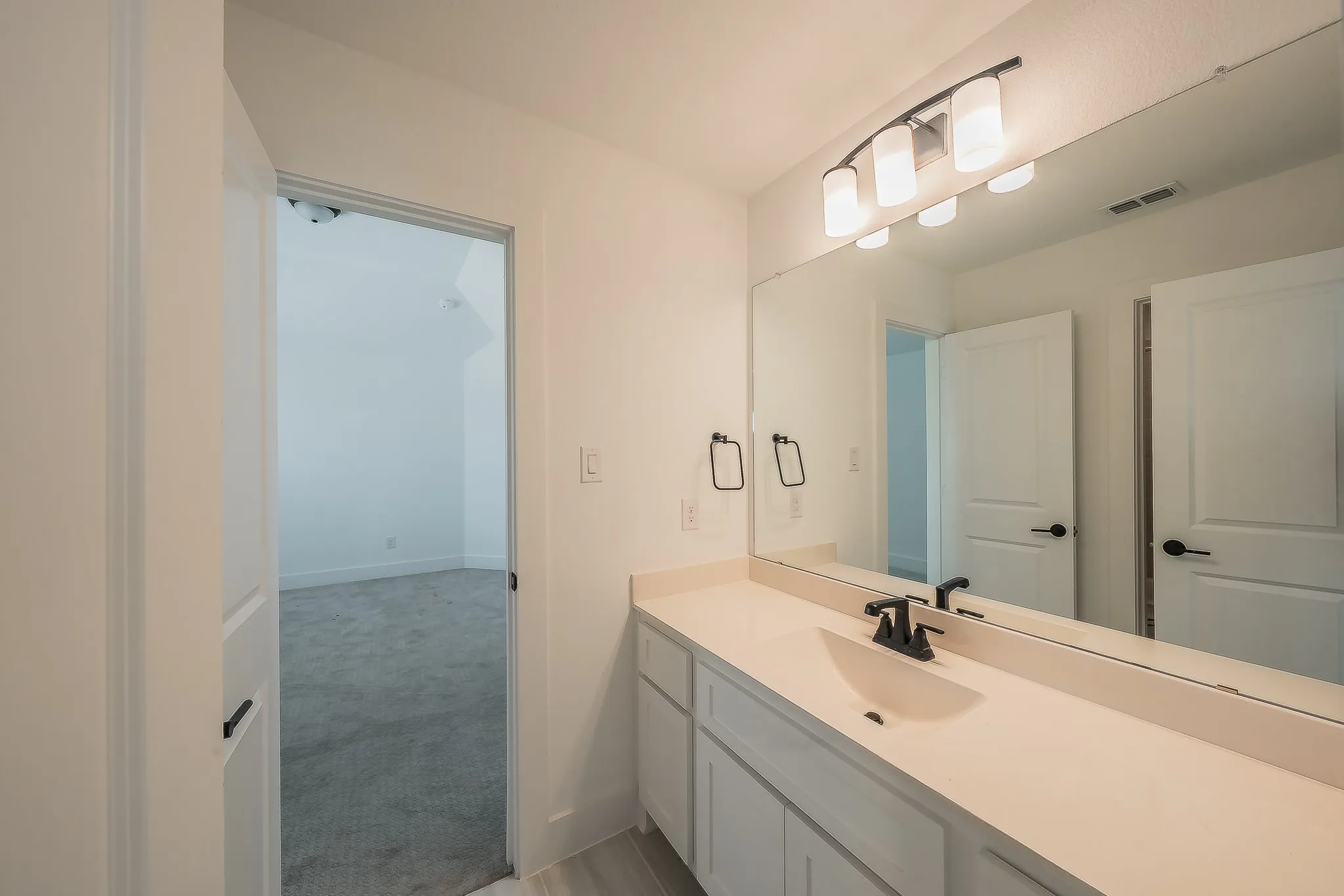 Vanity featuring a rectangular undermount sink, light-toned countertop, and matte black faucet