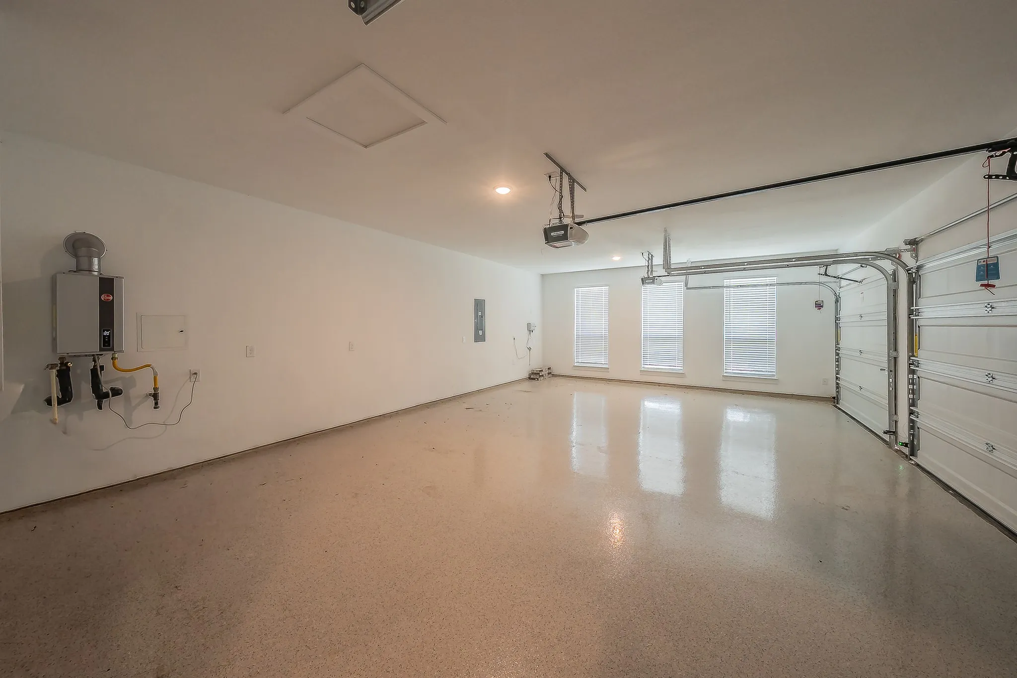 Spacious garage featuring an epoxy floor, three windows with blinds, and an overhead garage door