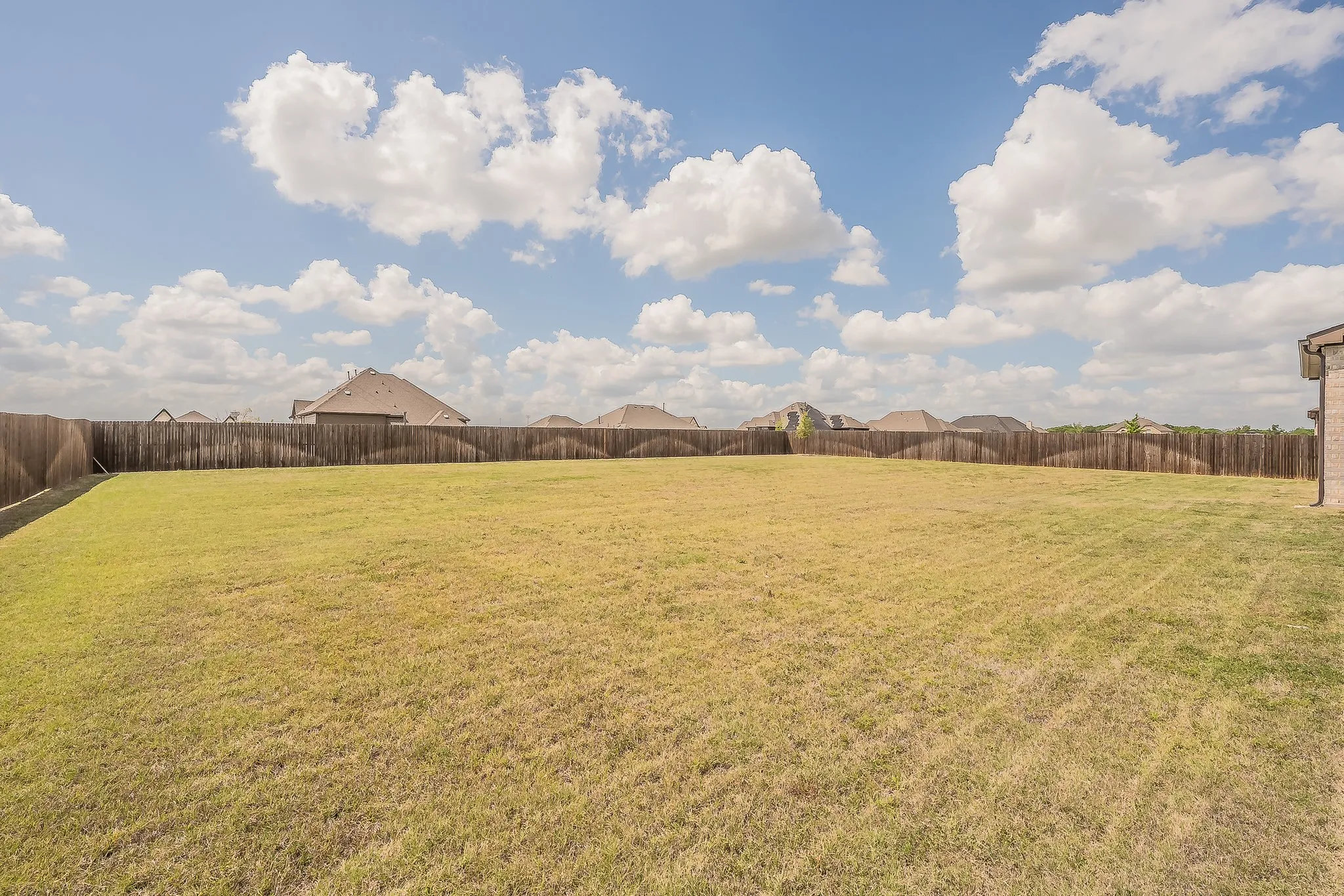 Expansive backyard with a wooden fence boundary and a large grassy area, offering ample outdoor space