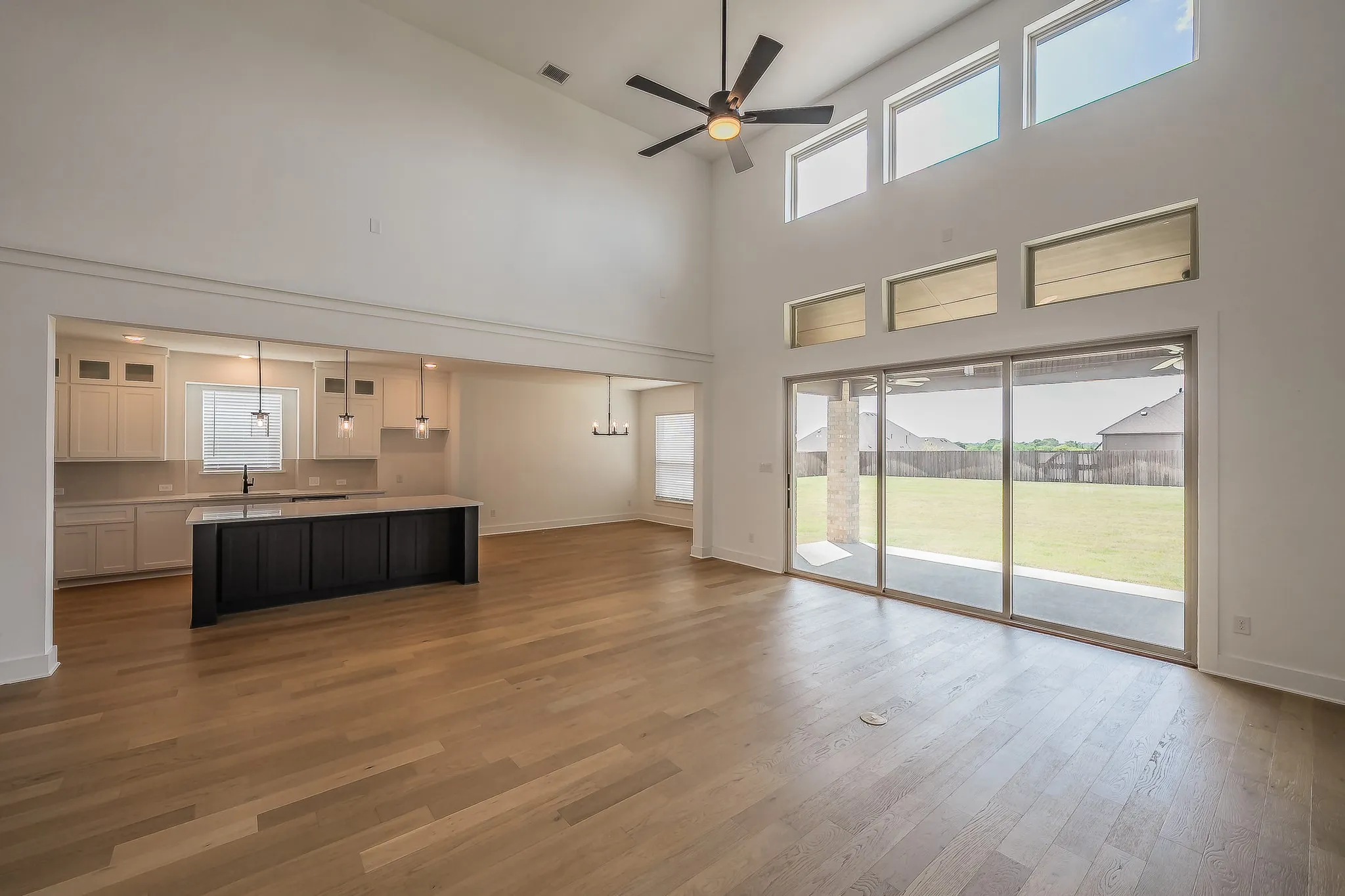 Open concept living area featuring hardwood flooring, a vaulted ceiling, and a ceiling fan
