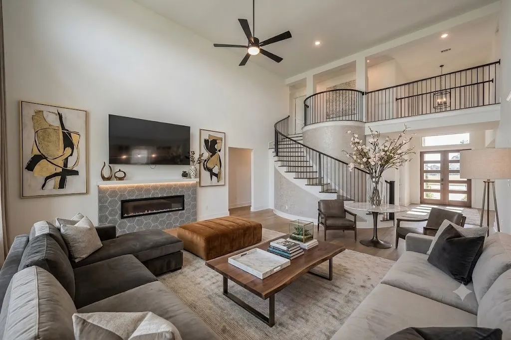 Spacious living area featuring a double-height ceiling, modern linear fireplace with hexagonal tile surround, and wood-finish flooring