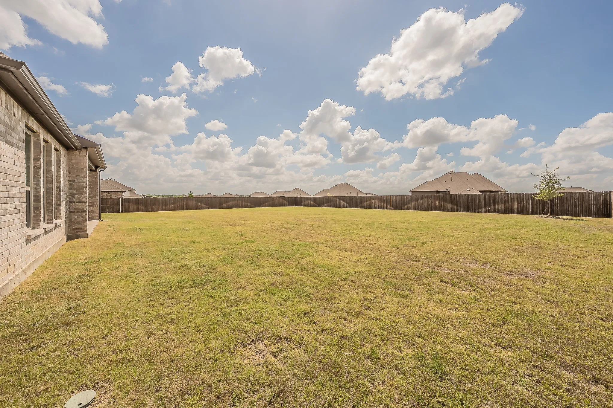 The property features an extensive backyard with a large lawn and a wood fence