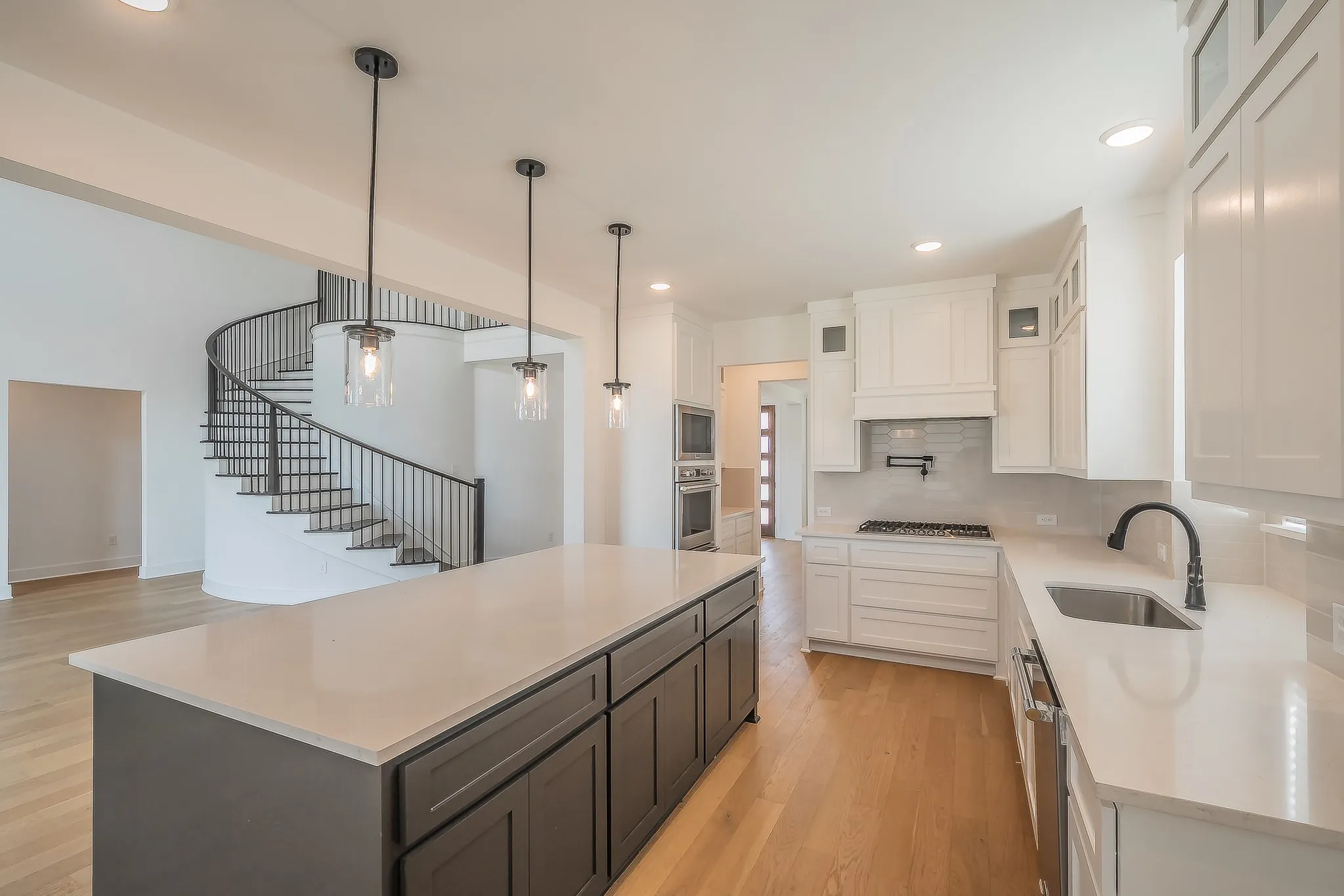 The kitchen features a large island with dark cabinetry, light countertops, and three pendant lights