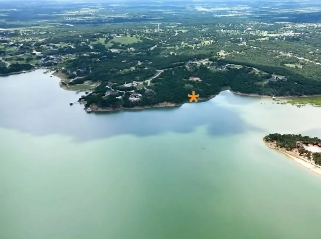 Expansive waterfront property situated on a prominent peninsula, featuring a natural shoreline and surrounding dense tree coverage