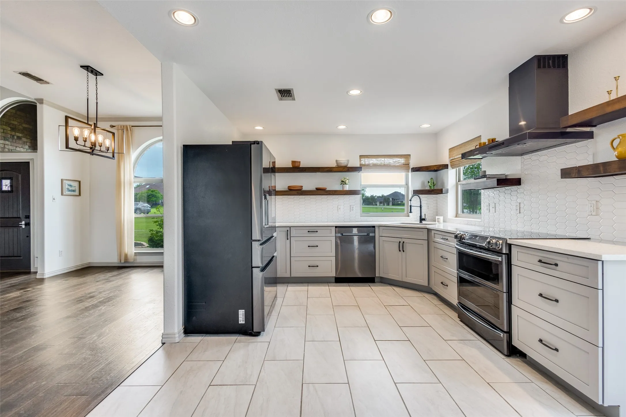 The kitchen features light-colored tile flooring, light grey cabinetry, white countertops, and white tiled backsplash