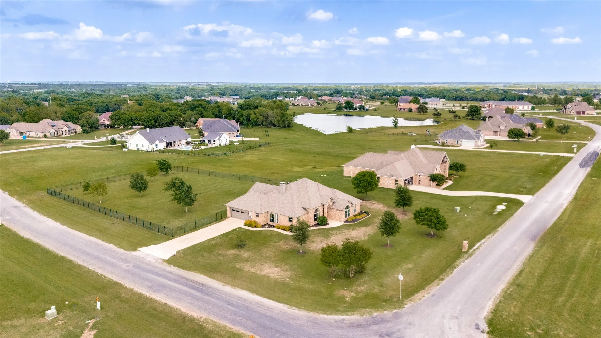 This property is situated on a corner lot, featuring a large, well-maintained lawn and a paved driveway leading to an attached garage