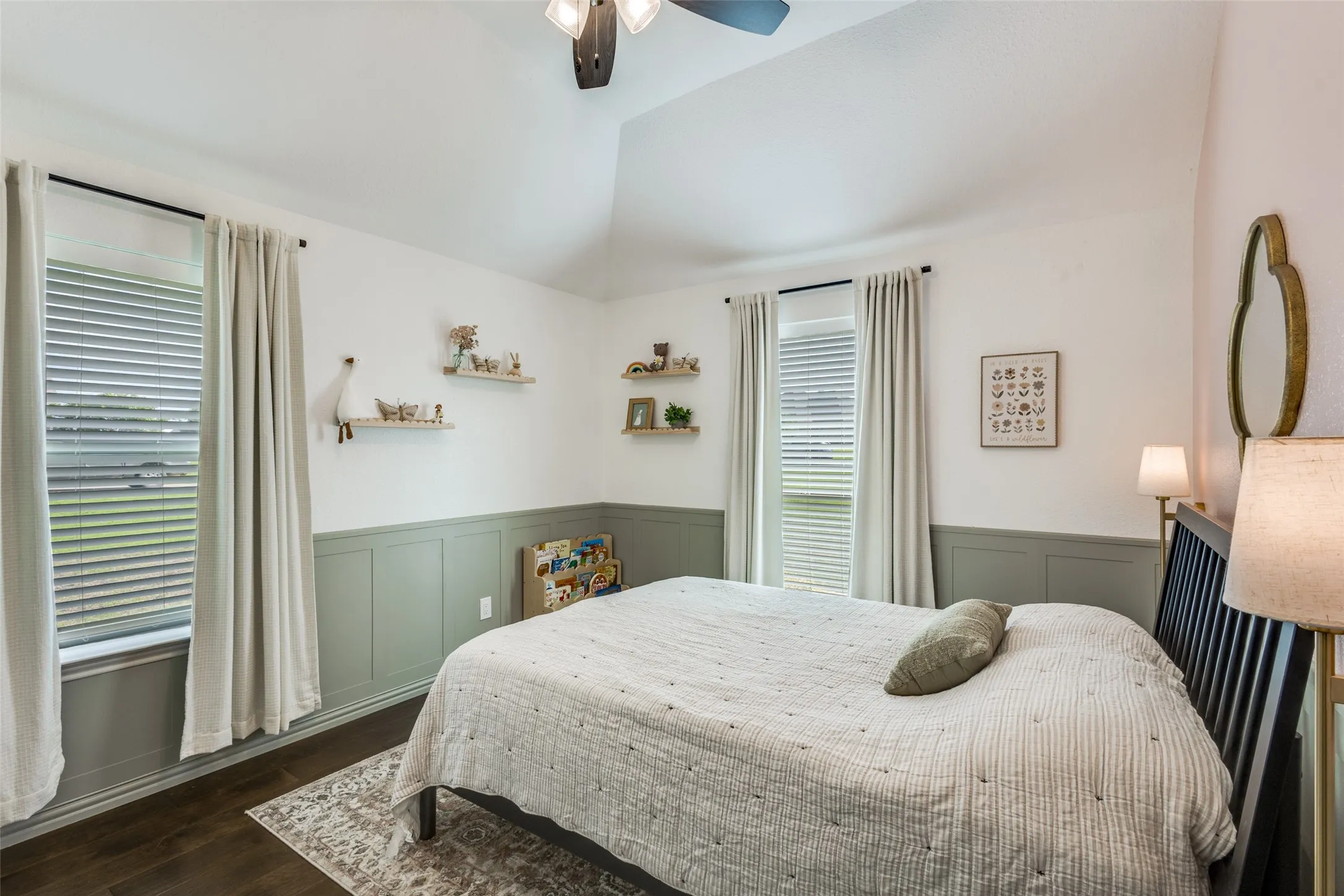 This room features vaulted ceilings, dark wood flooring, and wainscoting along the walls