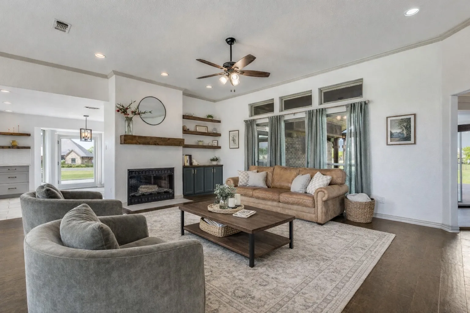 The living room features a fireplace with a wood mantle, recessed lighting, a ceiling fan, and large windows with transom panels above