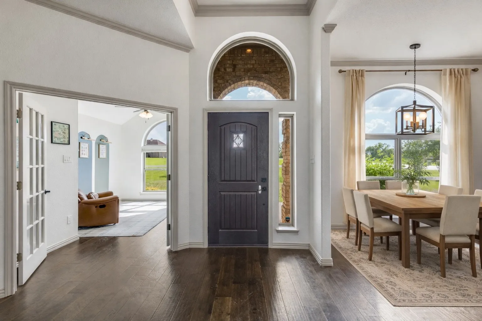 Entryway featuring dark wood flooring, a dark paneled front door with an arched transom window, and a sidelight