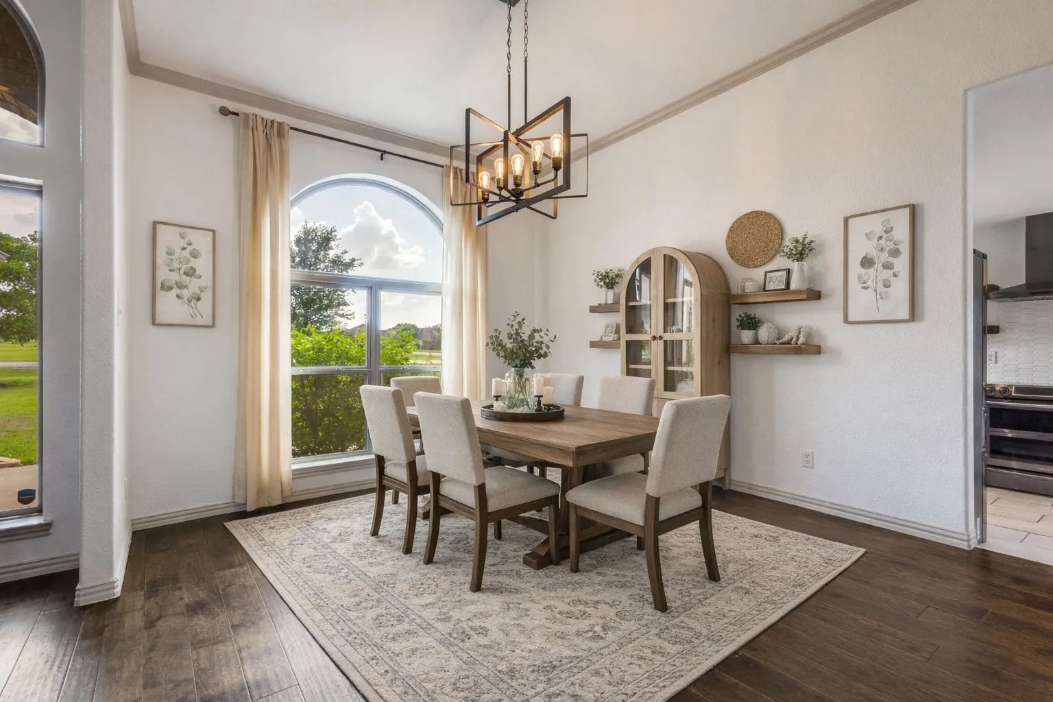 The dining area features dark wood floors, a large arched window, and a modern chandelier