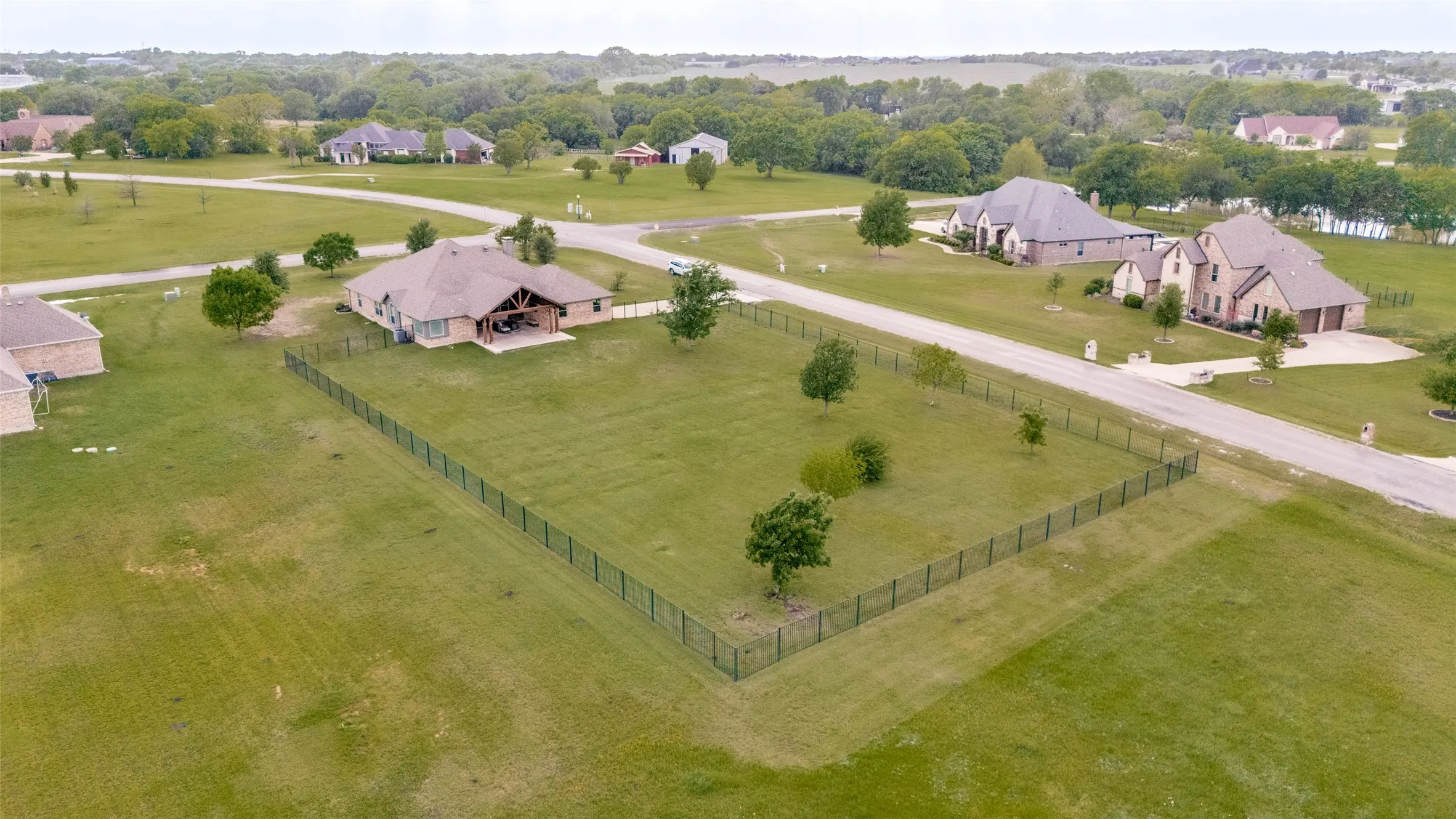 The property features an extensive fenced yard with a well-maintained lawn and scattered trees
