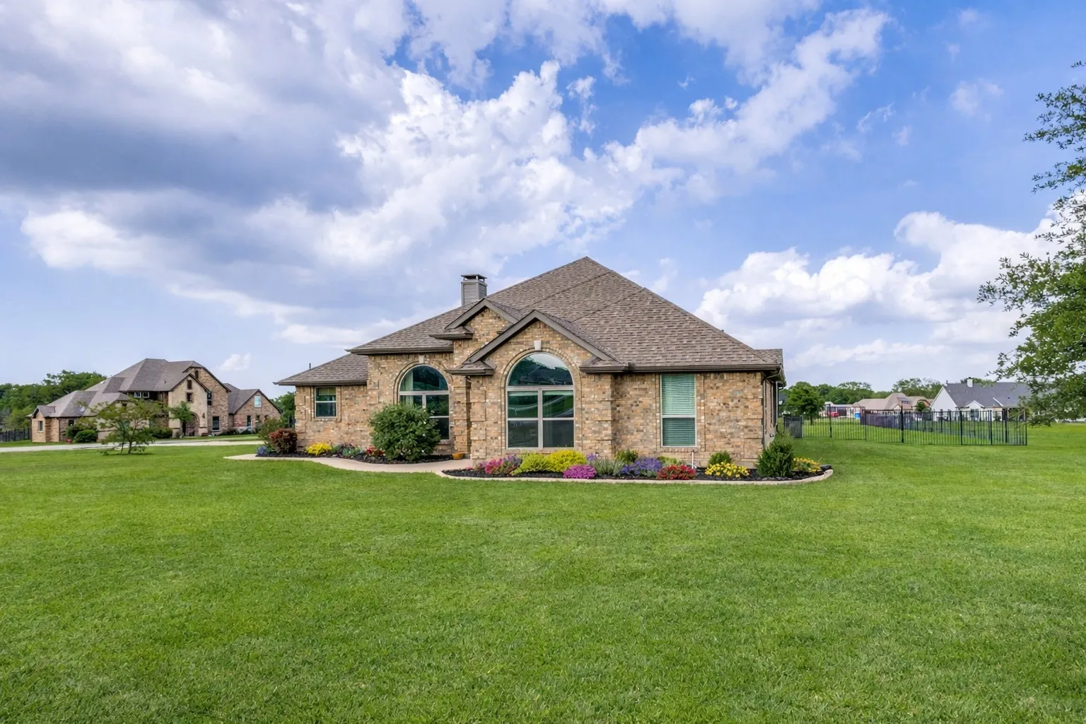 The property features a brick exterior, a well-maintained lawn, and landscaped flower beds