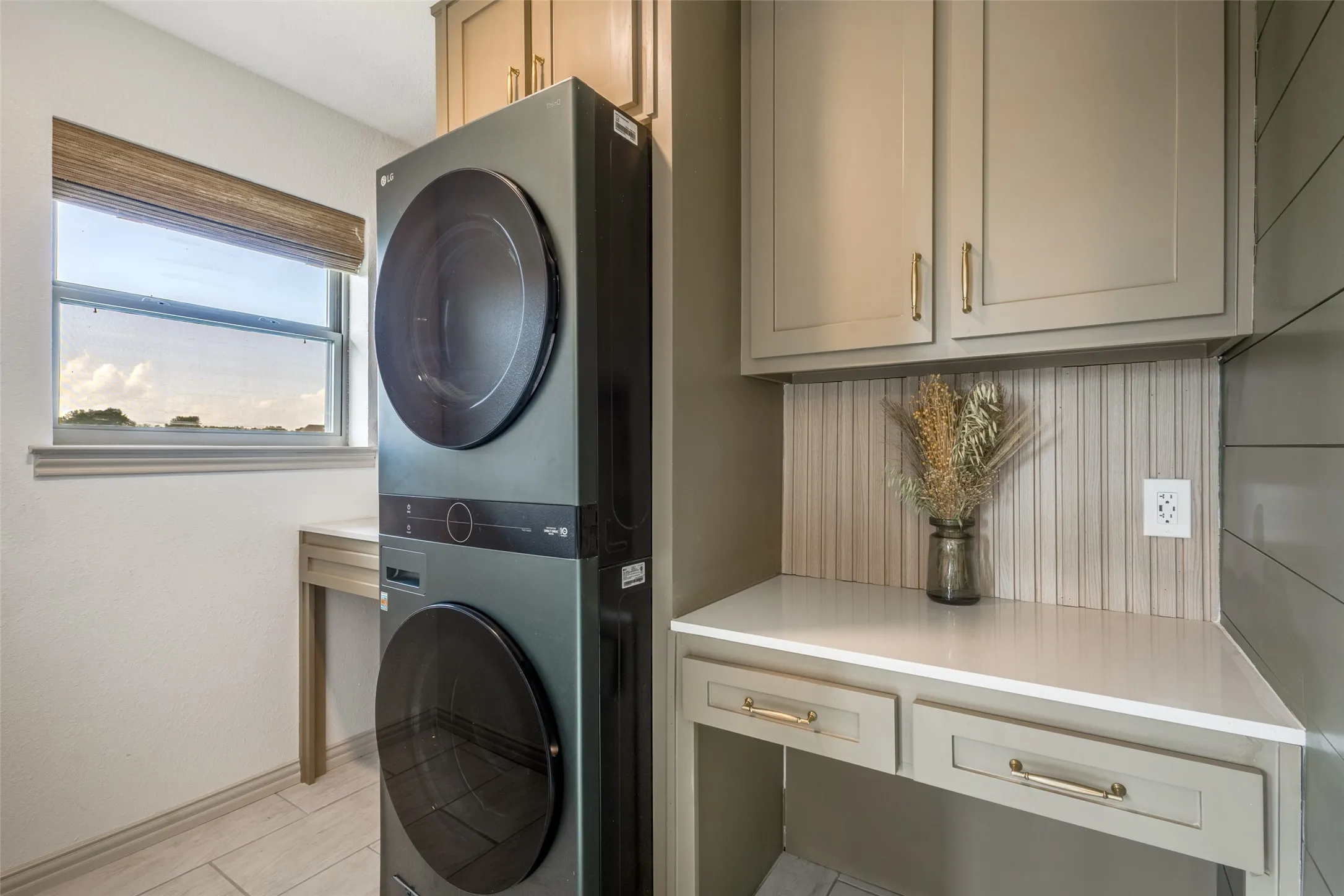 This utility area features a stacked washer and dryer, a window with a view, and built-in cabinetry with a countertop