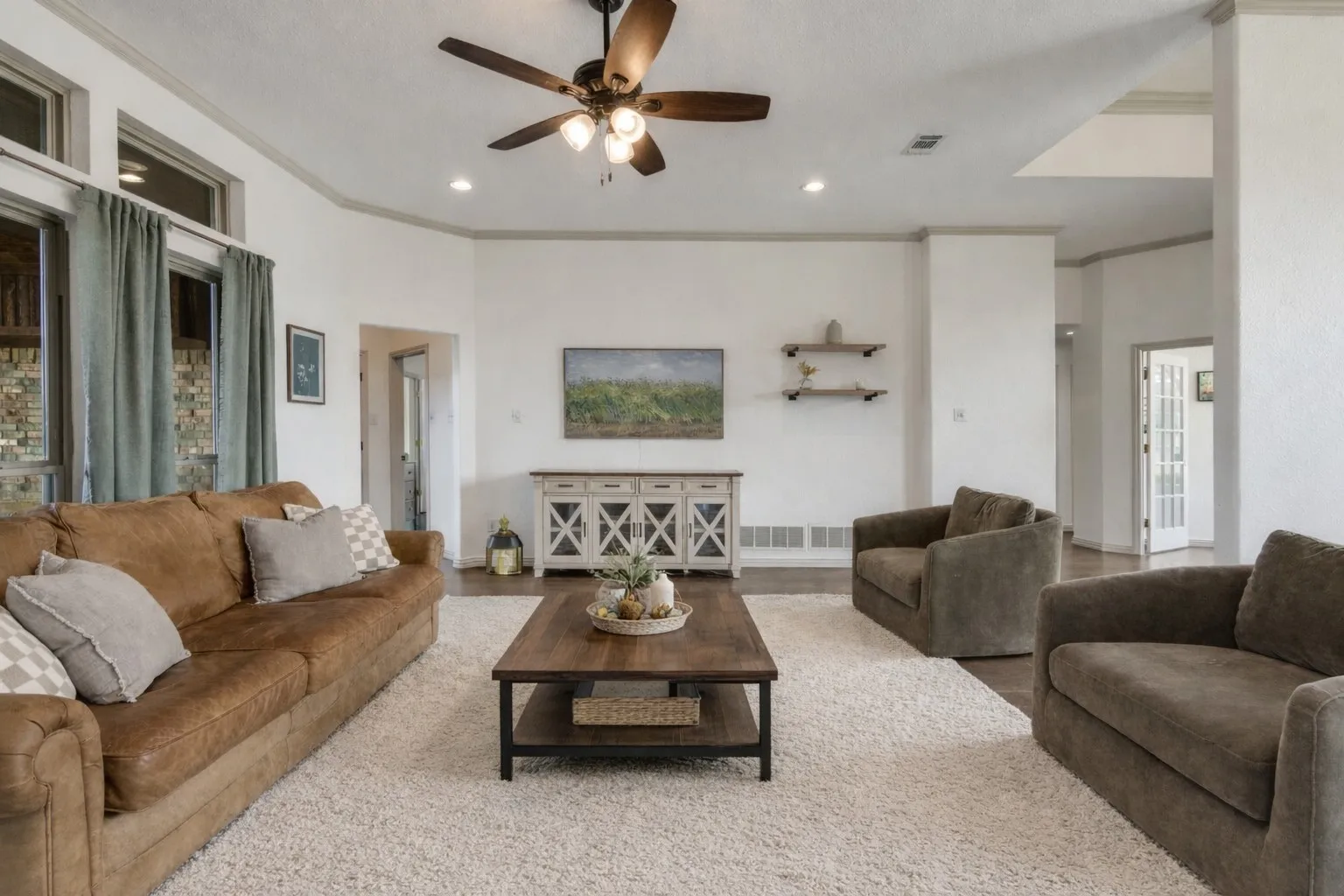 Spacious living area featuring a ceiling fan with integrated lighting, recessed lighting, and large windows with curtains