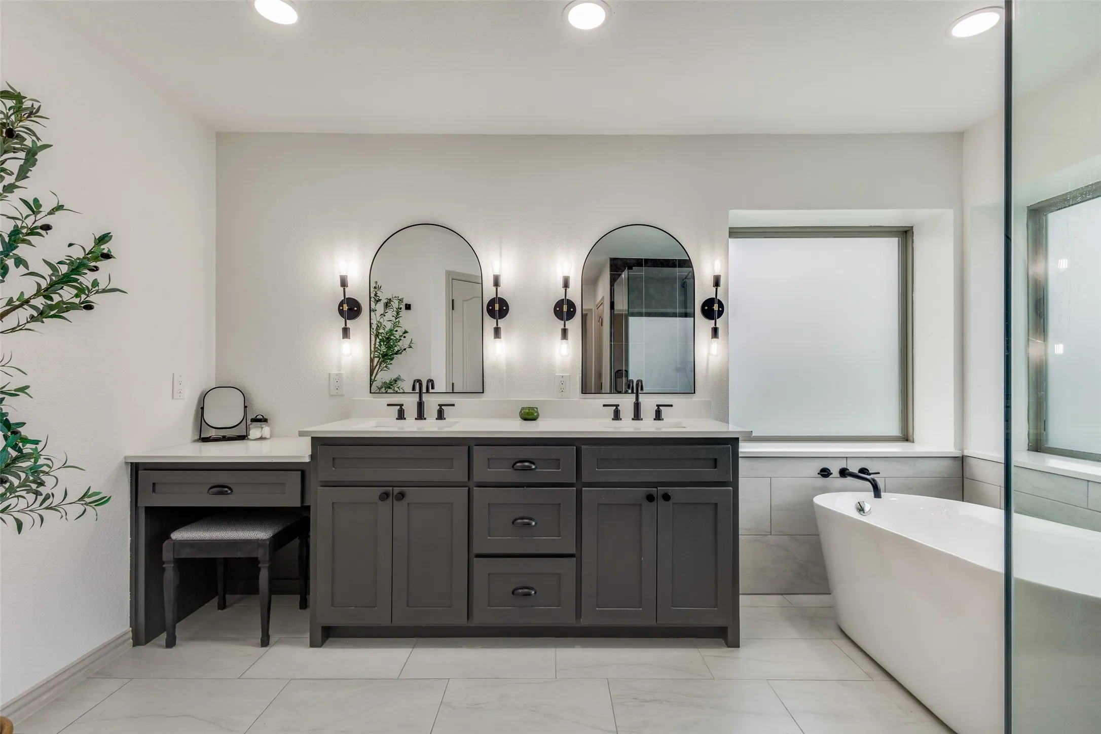 This bathroom features a double vanity with dark cabinetry, white countertops, and arched mirrors with sconce lighting