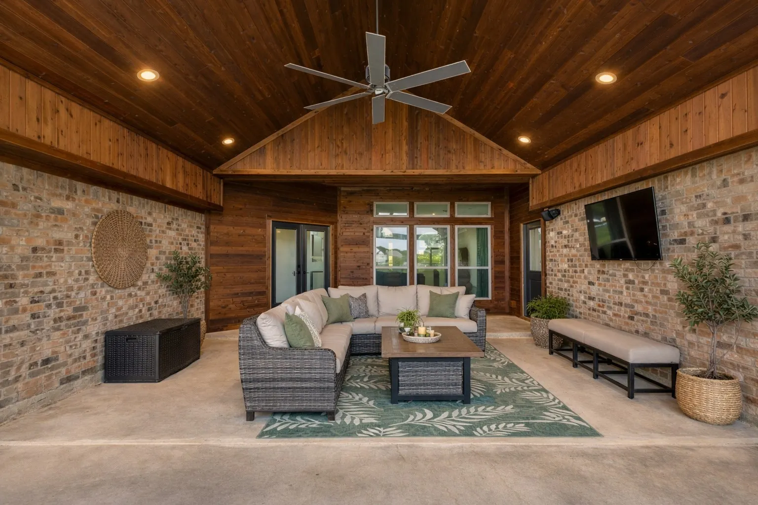 The property features an expansive covered patio with a vaulted wood plank ceiling, recessed lighting, and a ceiling fan