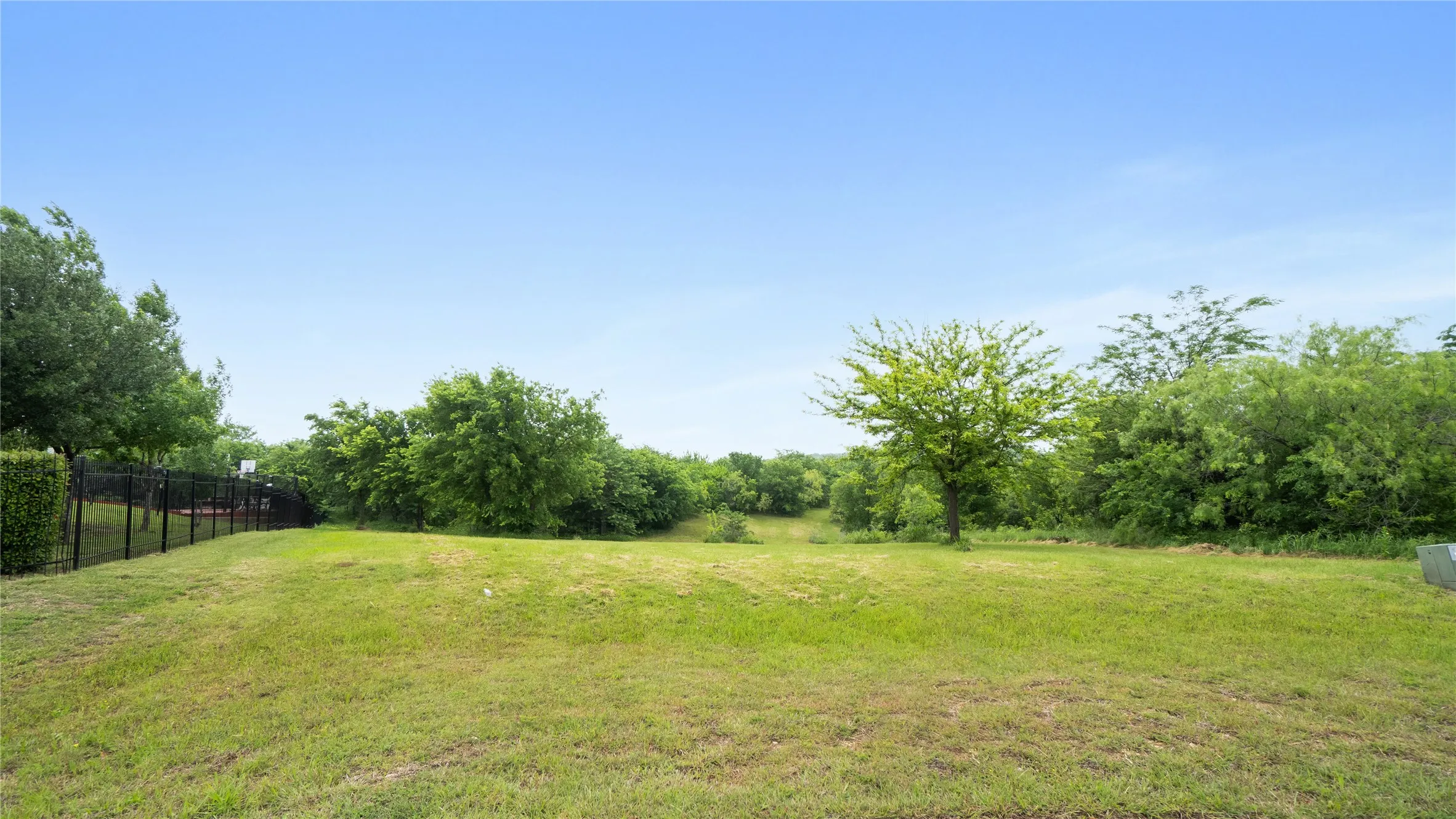 Expansive grass lawn with a black metal fence border