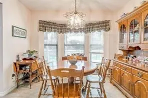 Dining area featuring a bay window, a chandelier, and a wood cabinet with glass doors