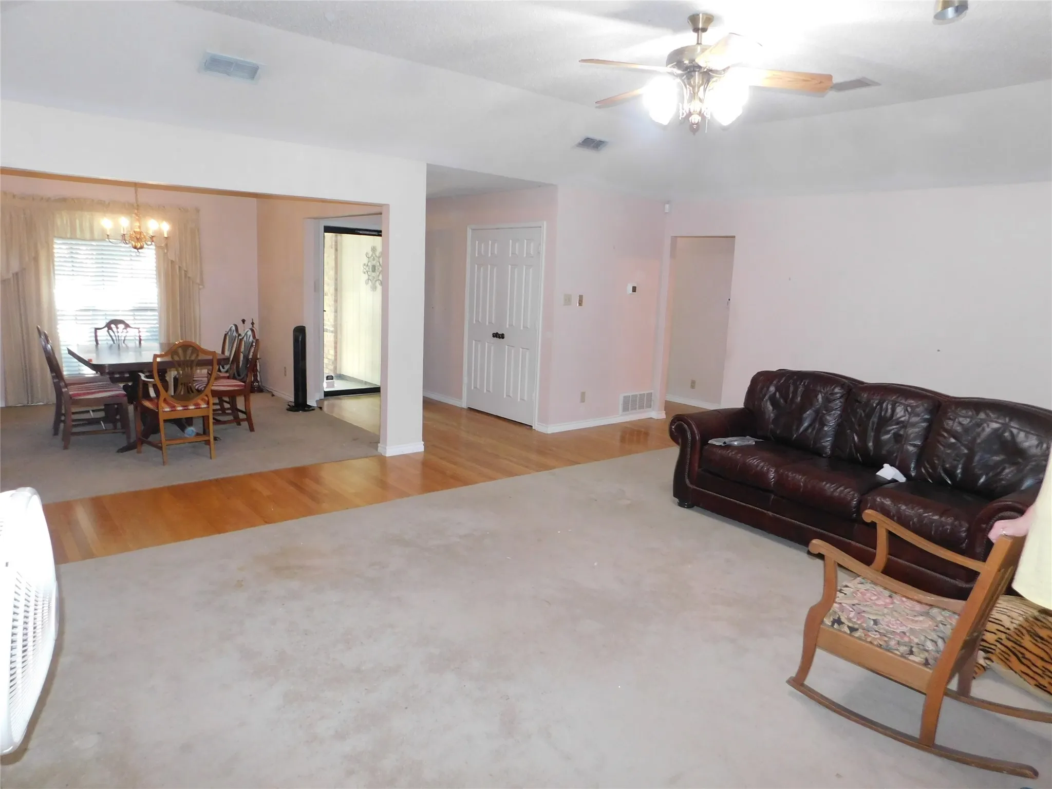 The property features an open-concept layout with carpeted and hardwood flooring, a ceiling fan, and a dining area with a chandelier