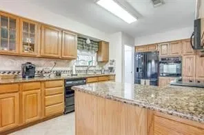 The kitchen features wooden cabinetry, granite countertops, and a full suite of black appliances