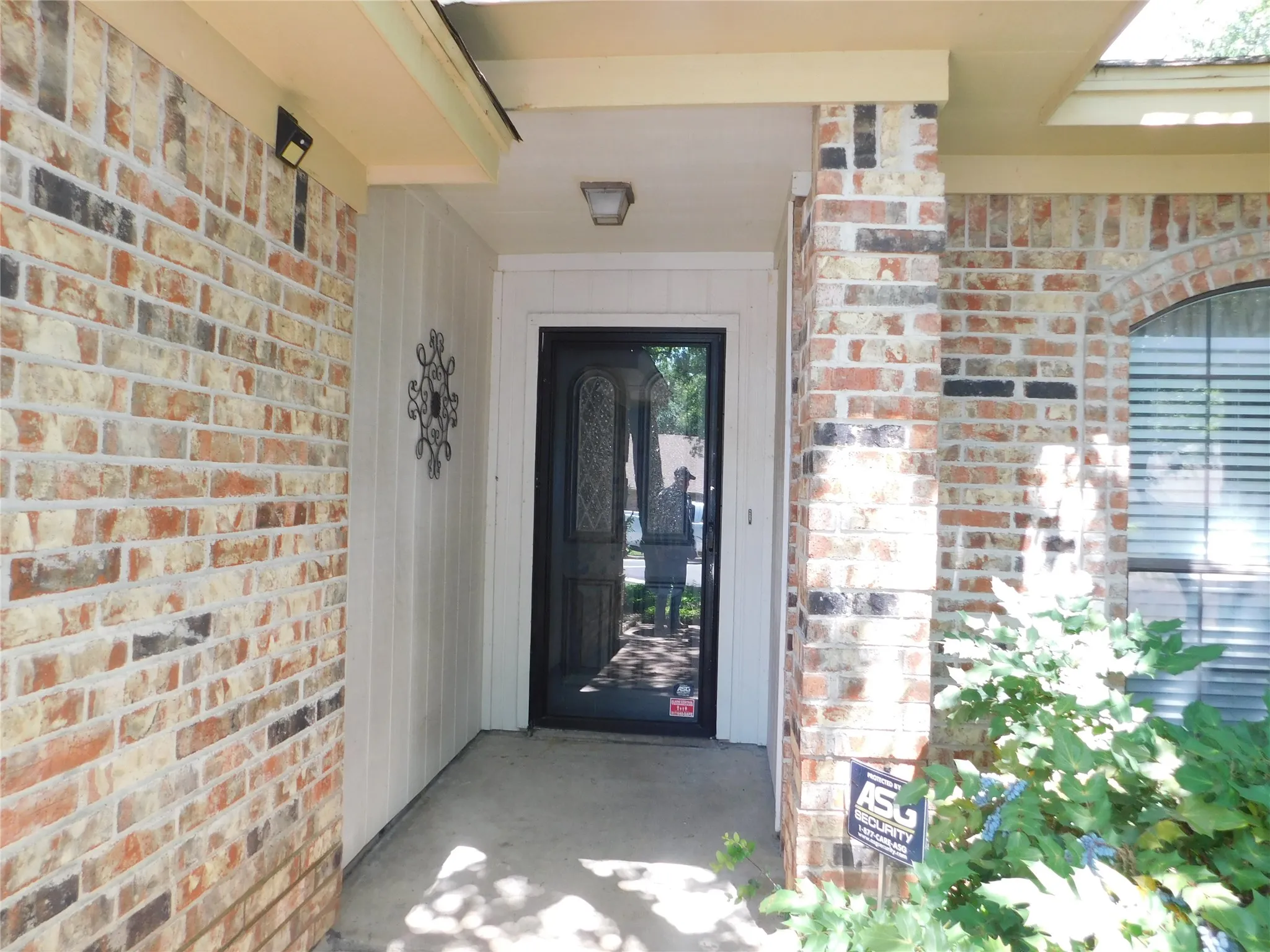 The property features a brick exterior with a covered entryway, a dark-colored front door, and an arched window with blinds
