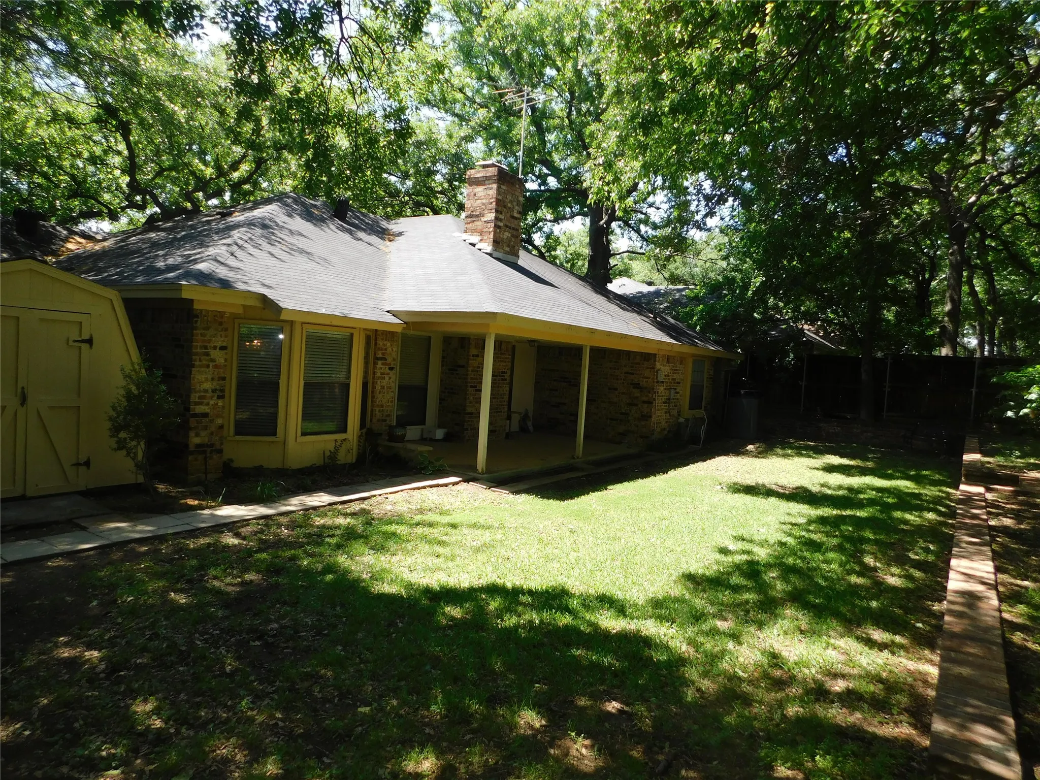 The property features a brick exterior, a covered patio area, and a well-maintained lawn