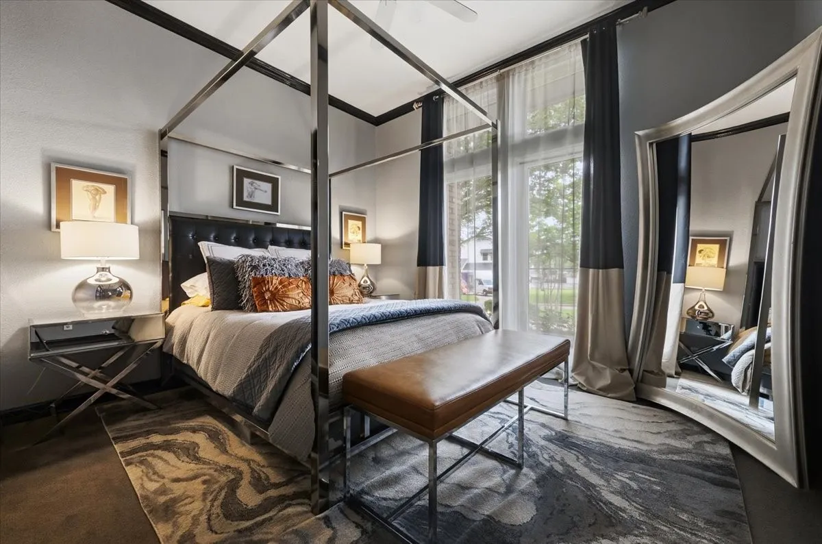 The guest BR  features a canopy bed frame, a decorative area rug, and full-height windows with curtains