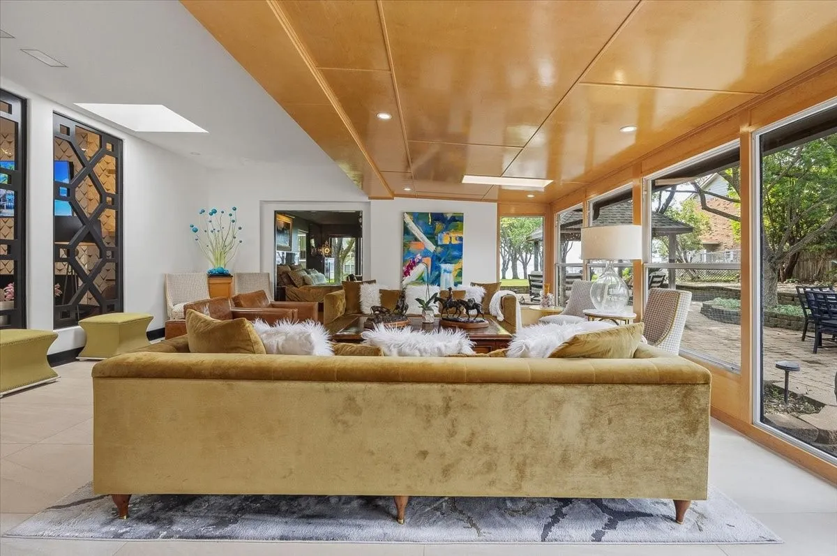  Expansive sunroom / living area with large windows for easy entertaining and  views of the exterior, featuring a bar area with seating, and decorative wall panels