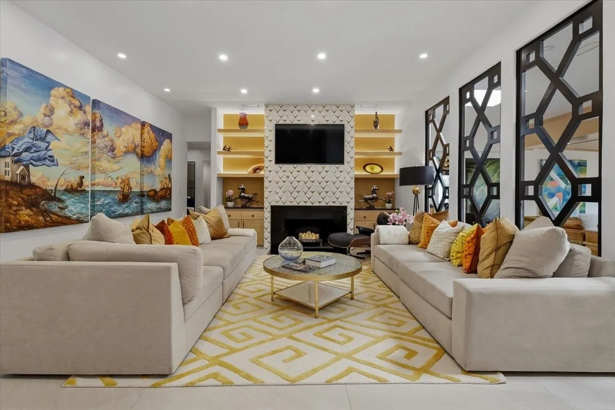 Living area features recessed lighting, a fireplace with marble & Brass decorative tiled surround, and built-in shelving with integrated lighting