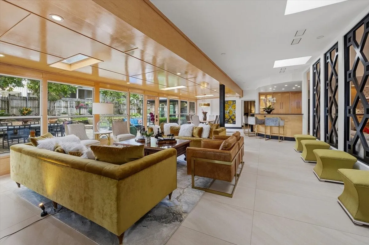 Expansive sunroom / living area with large windows for easy entertaining and  views of the exterior, featuring a bar area with seating, and decorative wall panels