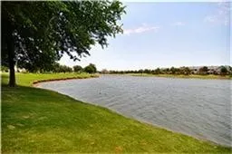 Expansive views of the lake with a lush green lawn and mature trees