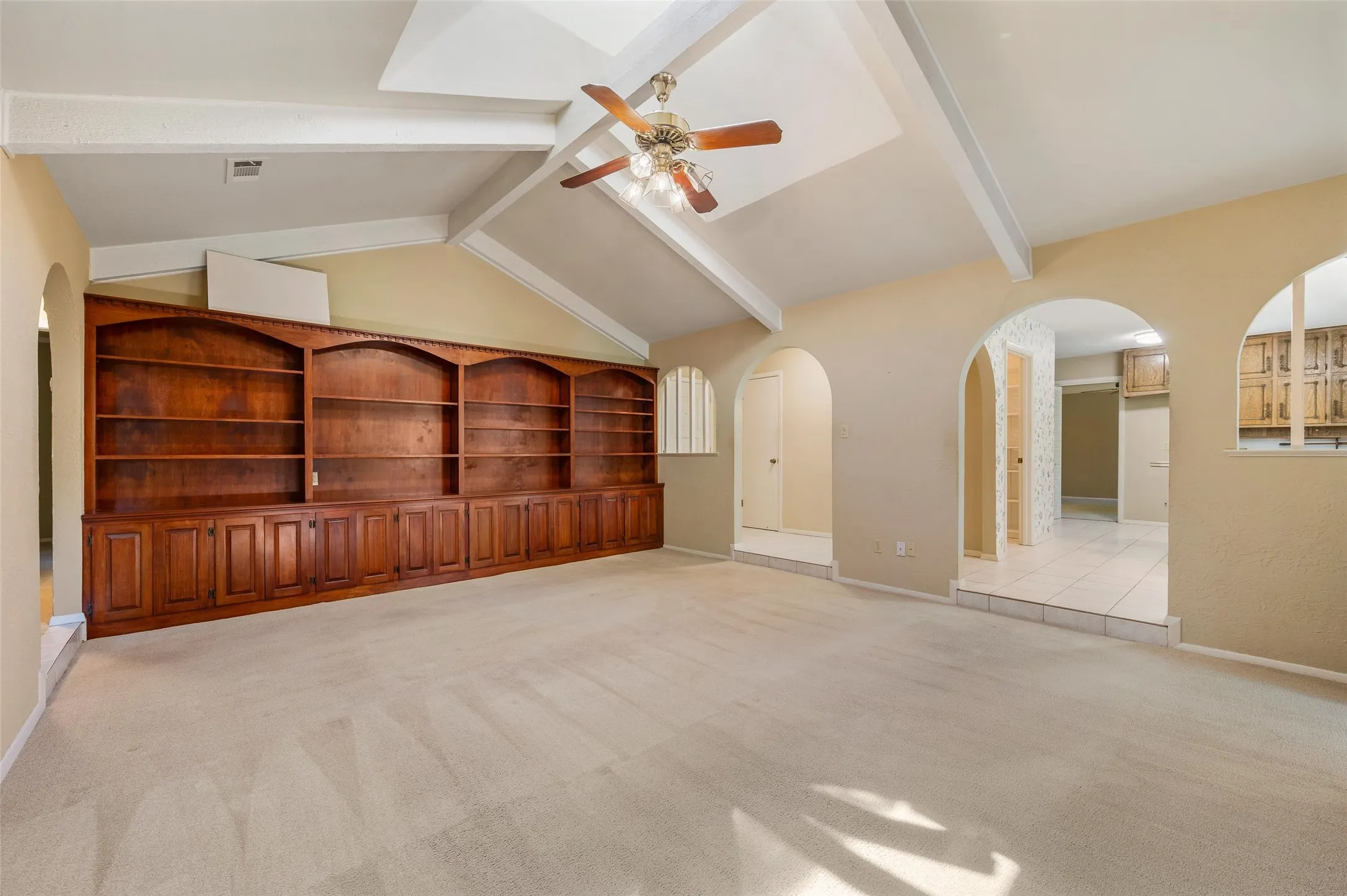 Elegant arched doorways, architectural cutouts, and a wall of built-in cabinets and shelves add character throughout the home.