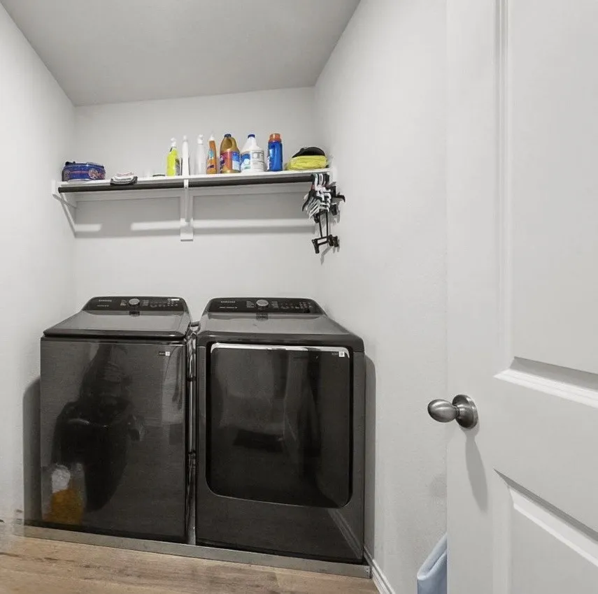 Dedicated utility space featuring wood-finish flooring and a white wall-mounted shelf