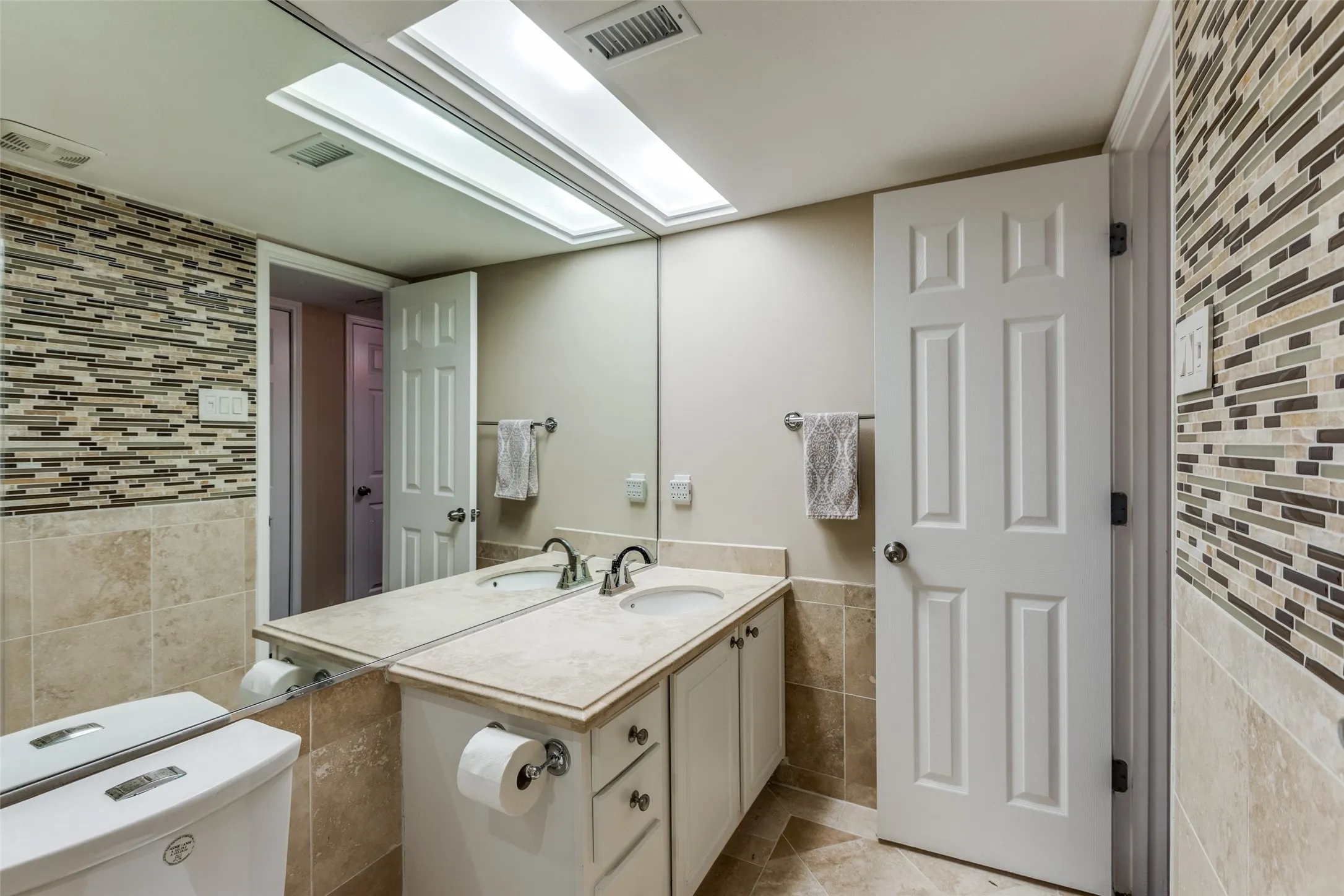 Bathroom featuring tile flooring, tile walls, vanity, and toilet