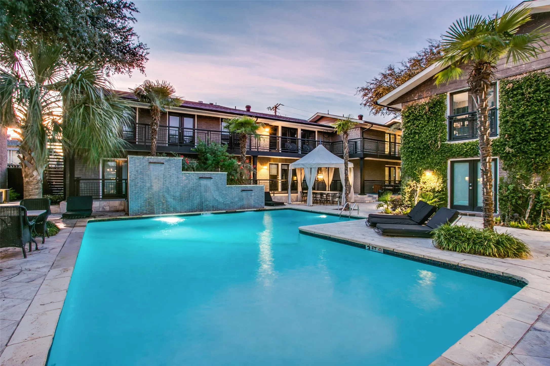 Sparkling pool with large seating and lounge area with beautiful decorative waterfall.