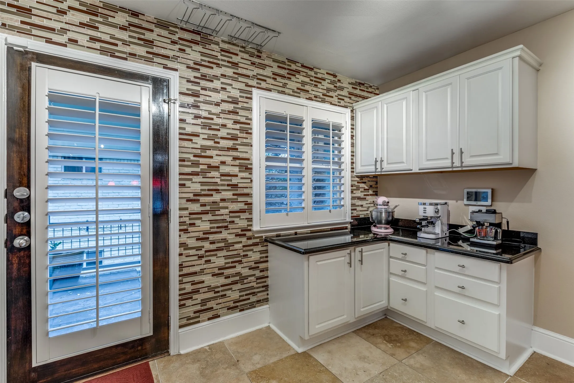 Designer touches throughout this light filled kitchen with plantation shutters on the windows and patio doors.
