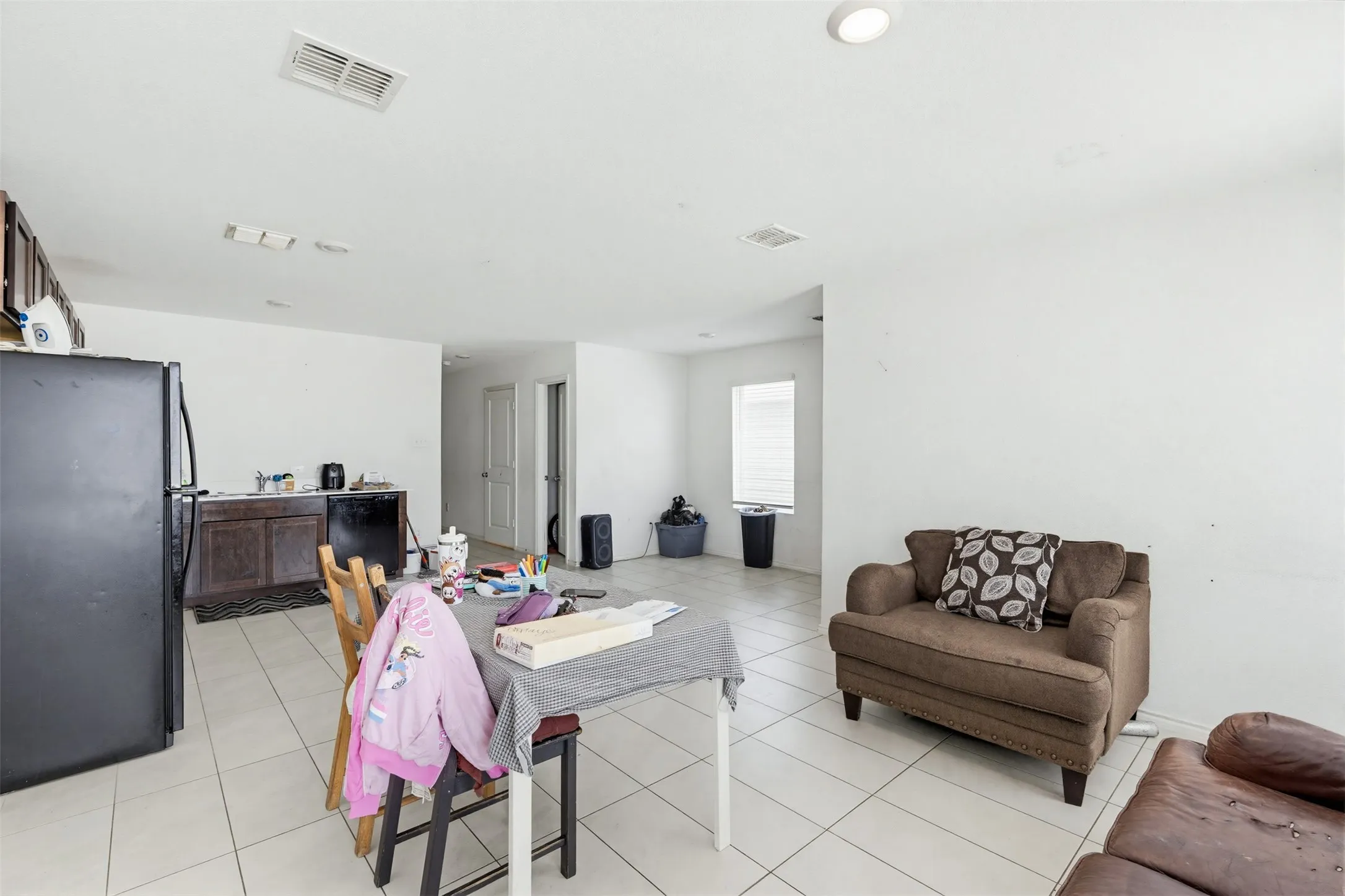 Open-concept living area with tiled flooring, white walls, and recessed lighting