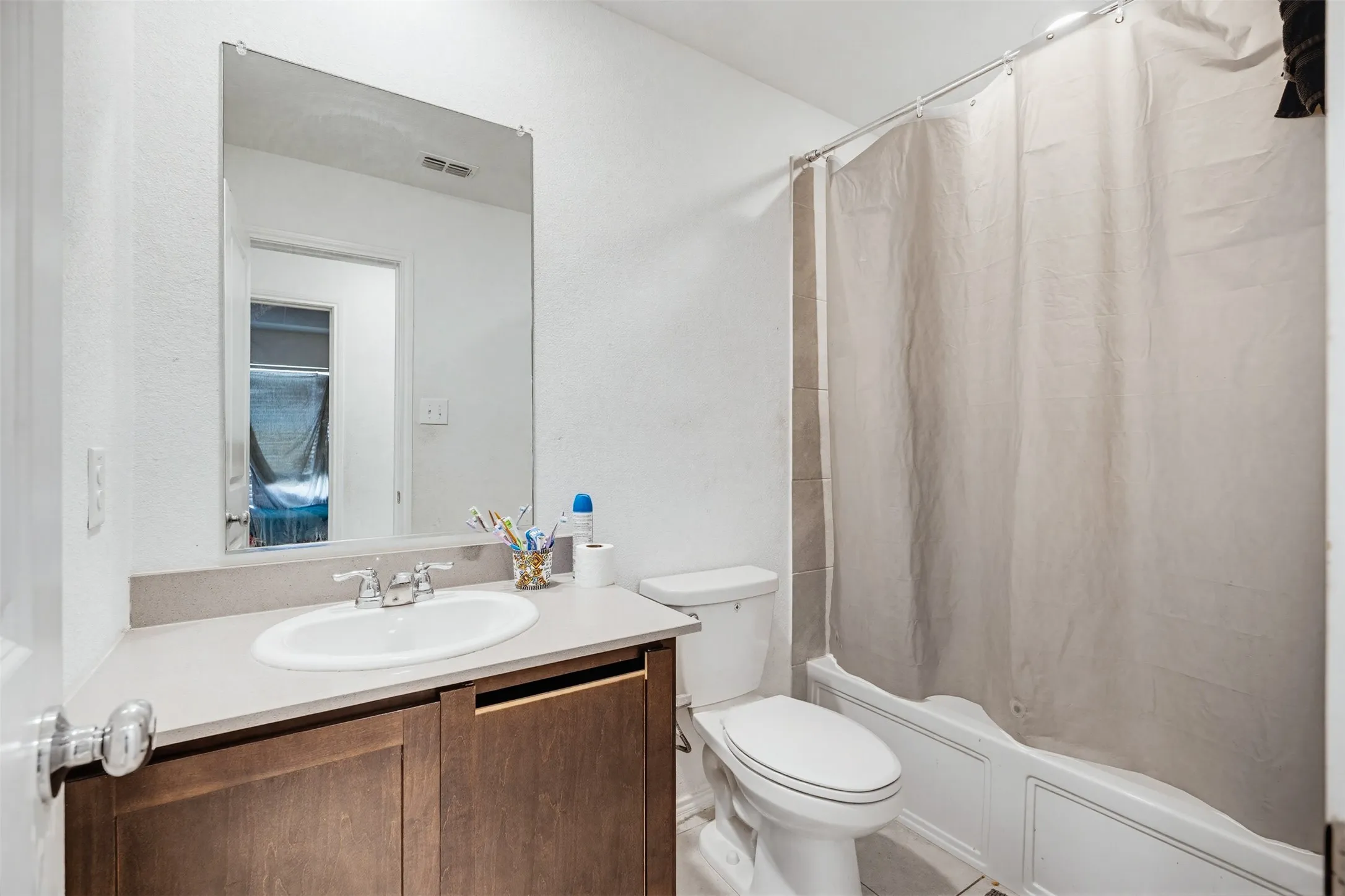 Bathroom featuring a vanity with a white sink, a mirror, and a shower with a shower curtain