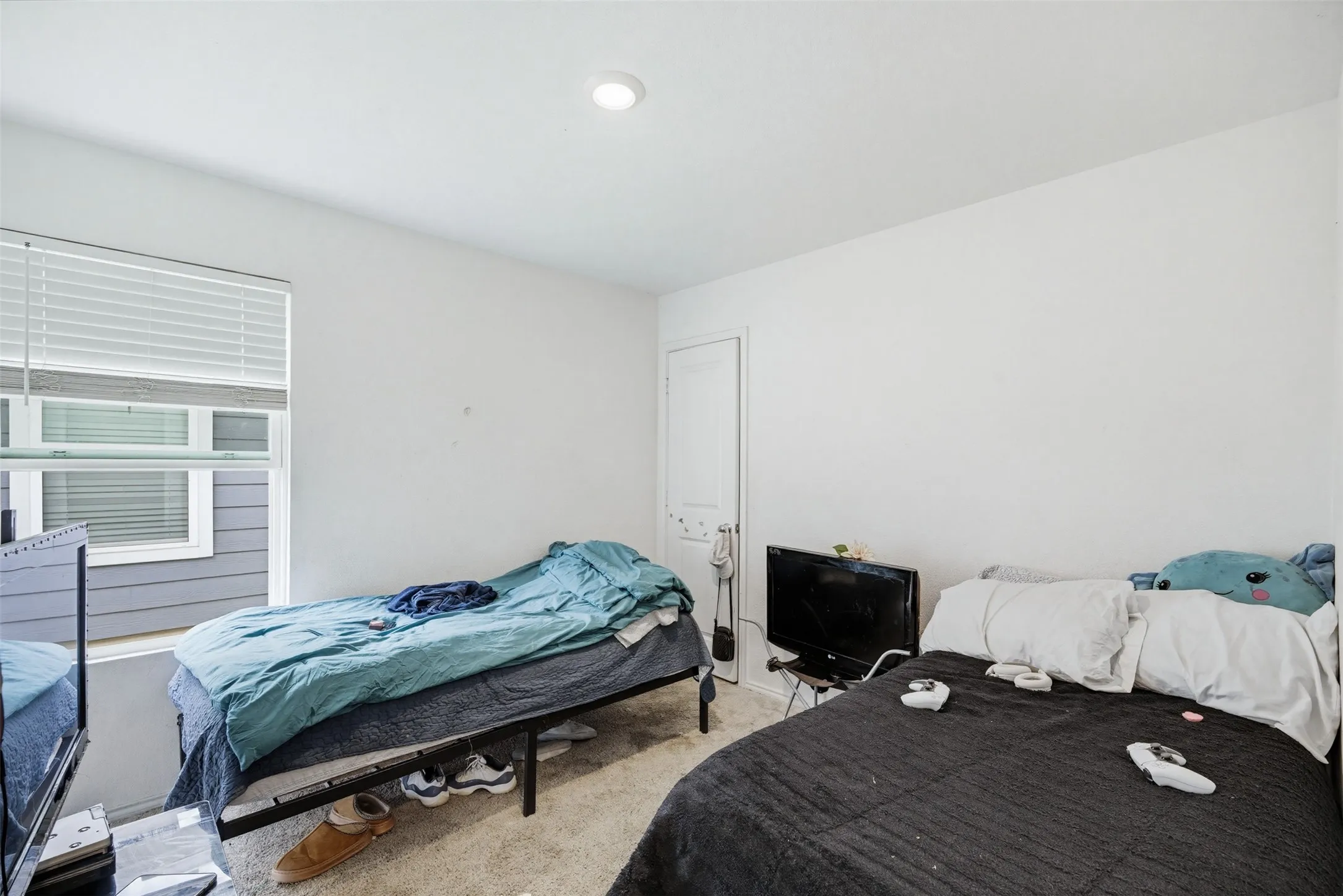 The room features a window with blinds, carpeted flooring, and white walls