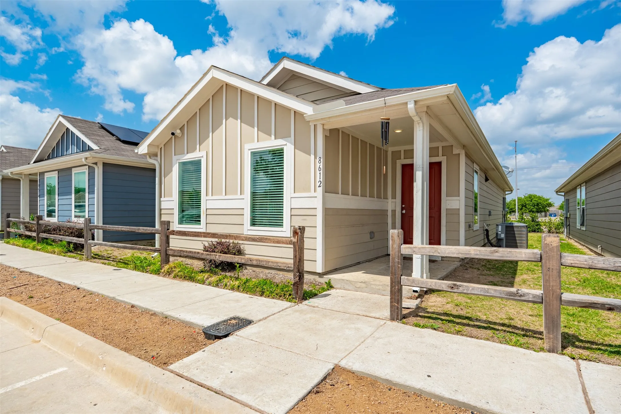 The property features a charming exterior with a covered porch and a red front door