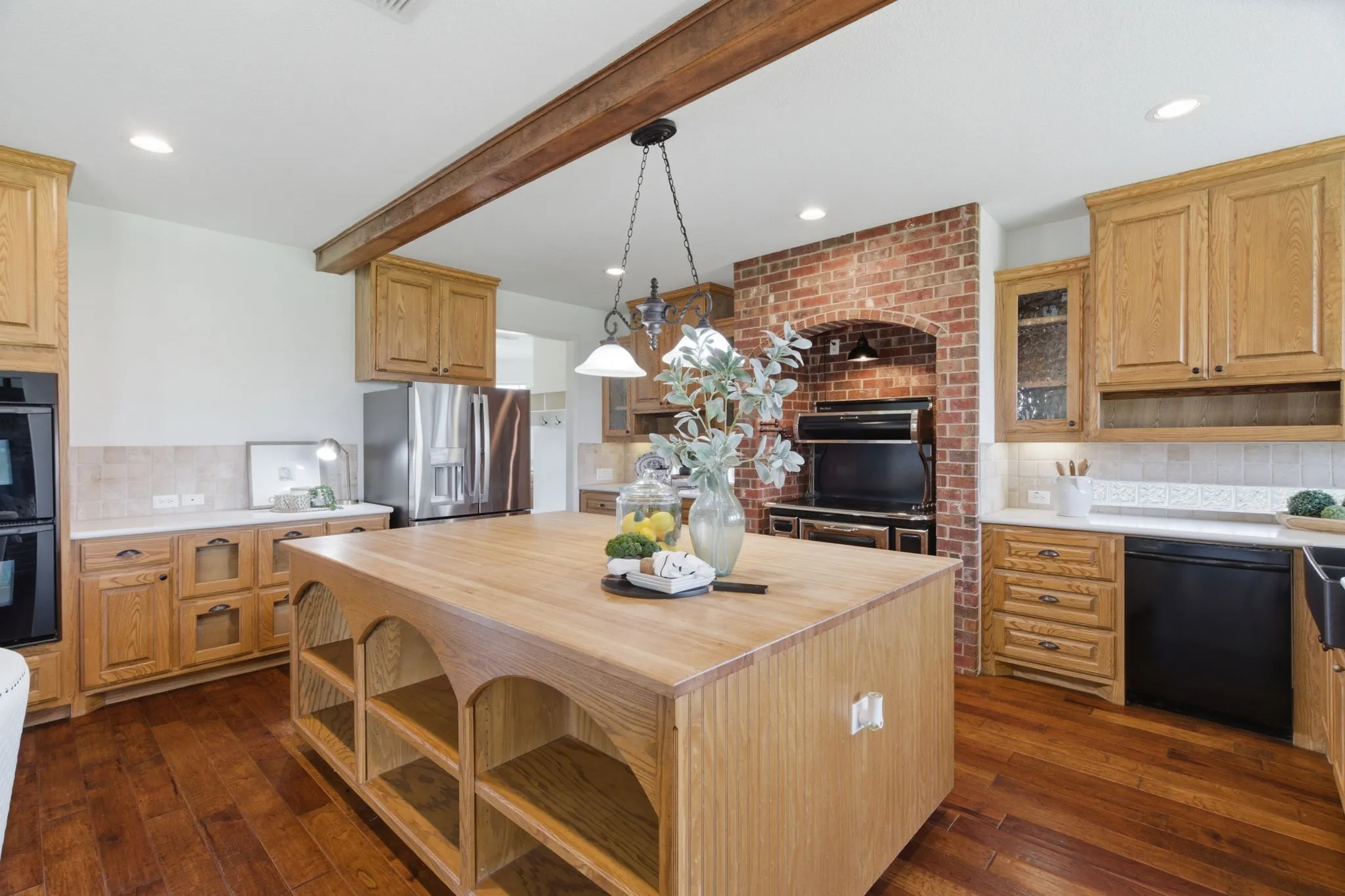 The oversized kitchen island, extensive cabinetry and distinctive brick range surround anchor the heart of this Springtown, TX home.