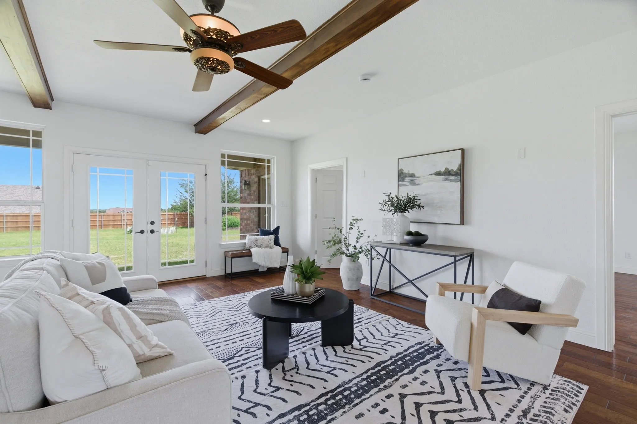 French doors and large windows fill the living room with natural light while opening the view toward the one-acre Springtown property.