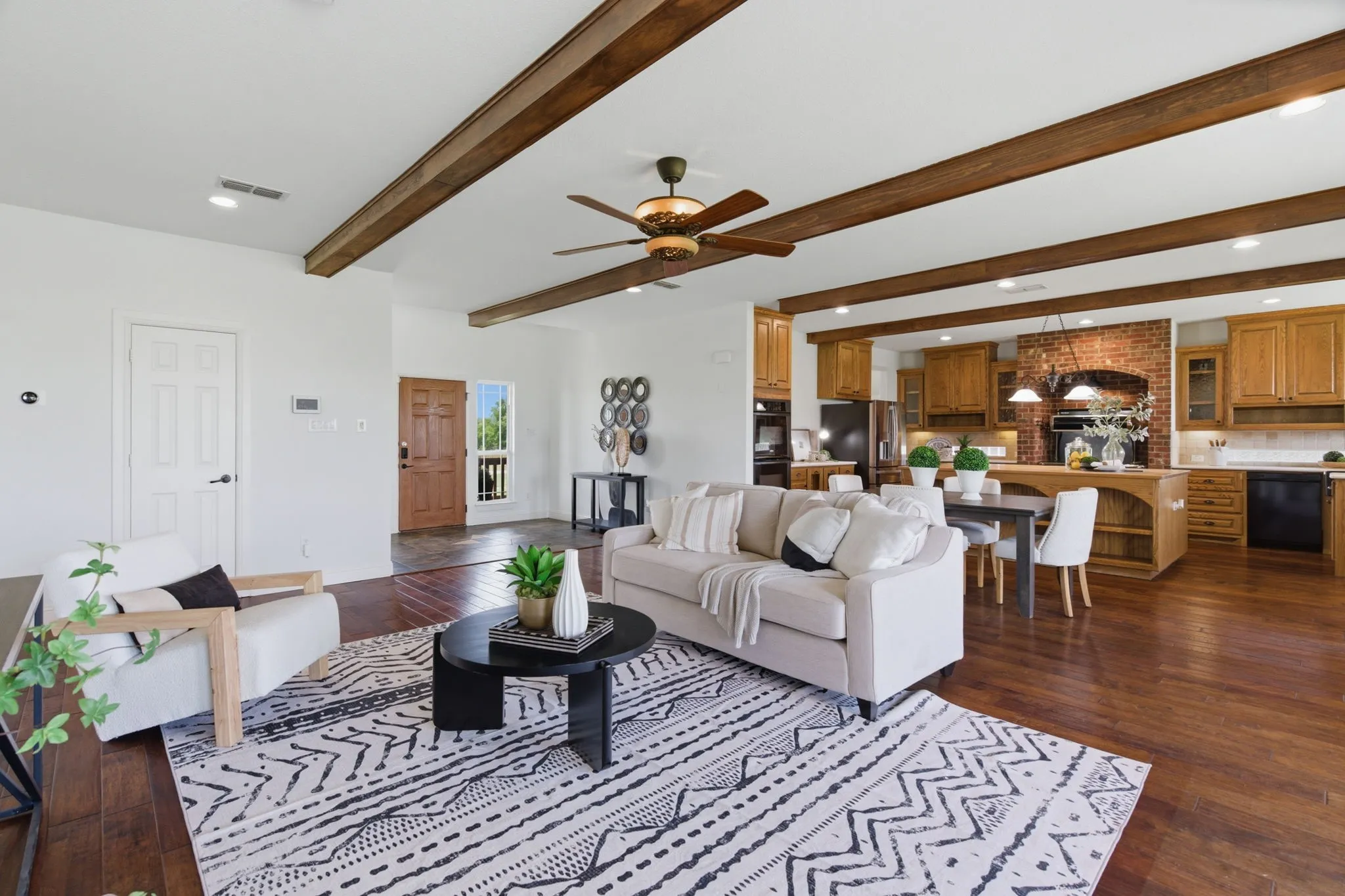 One of the home's standout spaces, the open living room flows directly into the kitchen beneath warm wood beams and soaring ceilings.