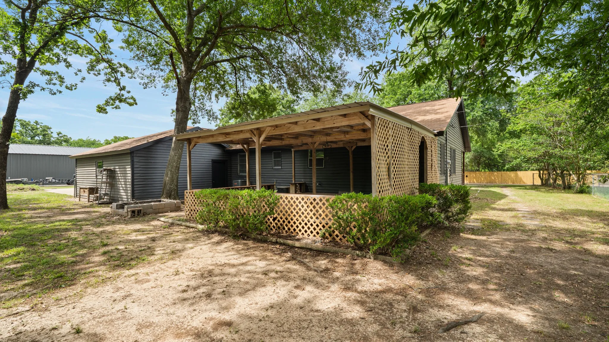 The property features a covered porch with lattice screening, set against a backdrop of mature trees