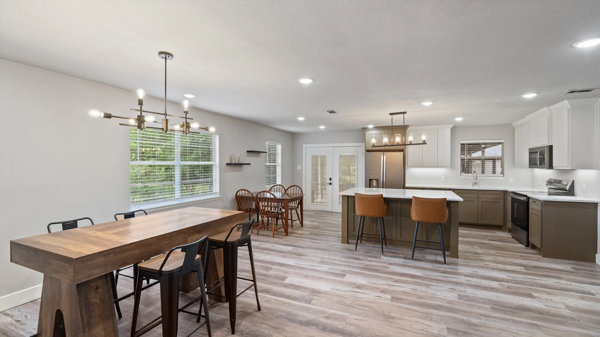 Spacious open-concept living area featuring light-toned flooring, recessed lighting, and a modern kitchen with a central island
